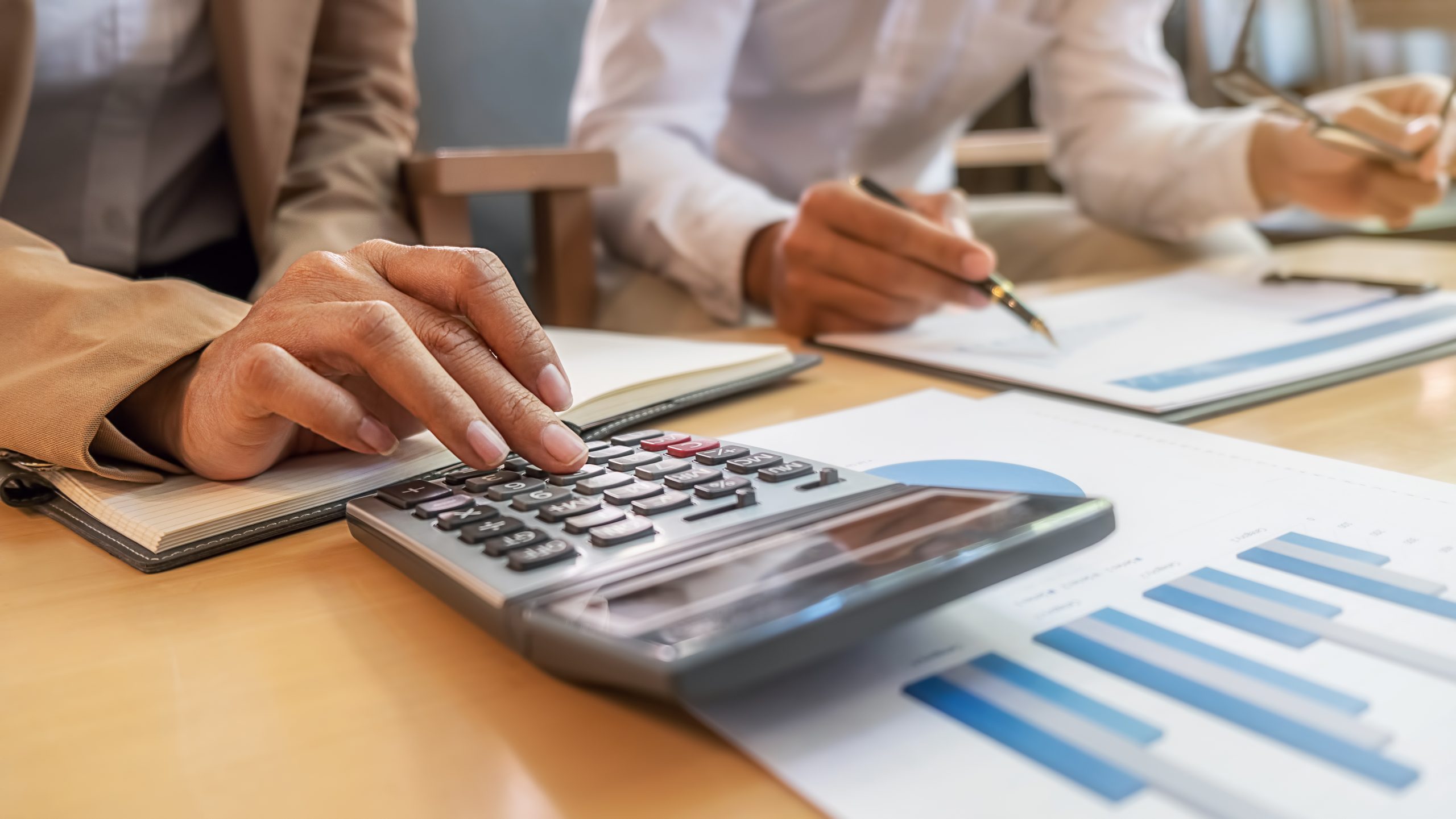 Two people work at a desk with a calculator.