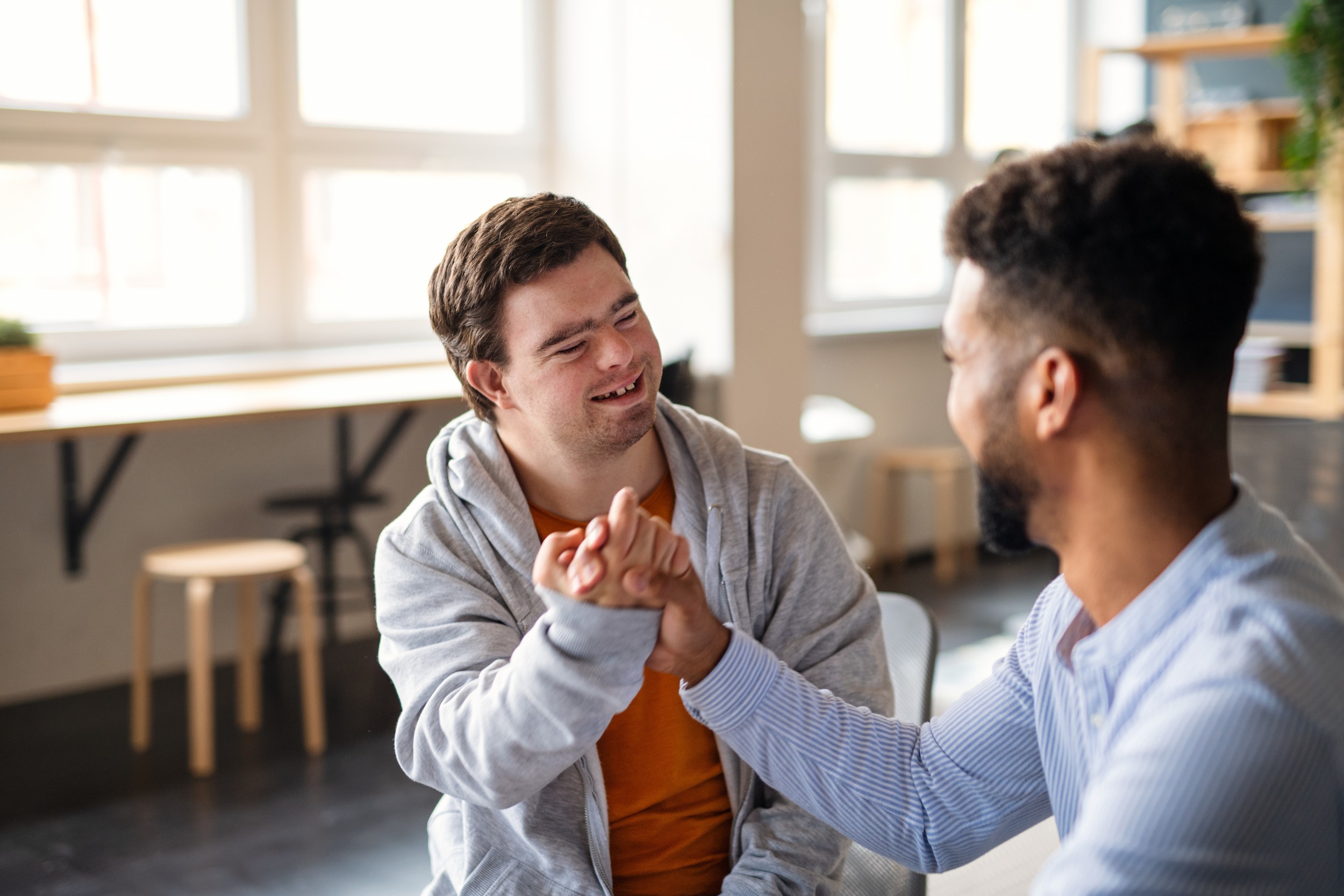 Young man holding hands with a man with Down syndrome