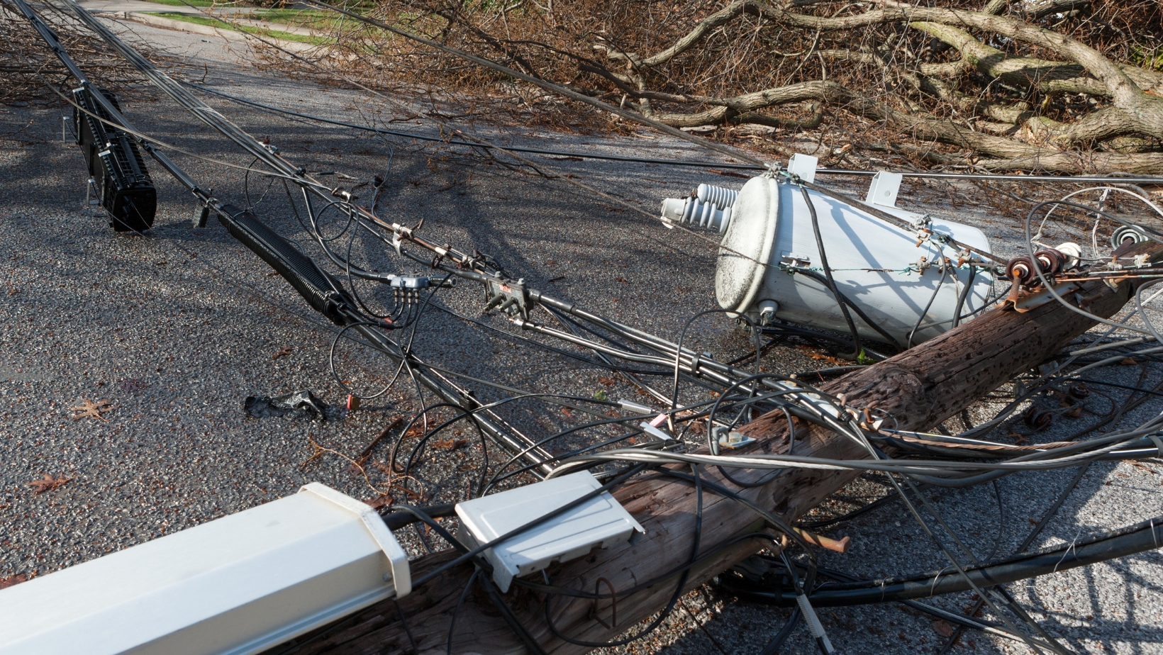 A downed hydro pole lays across the road with power lines.