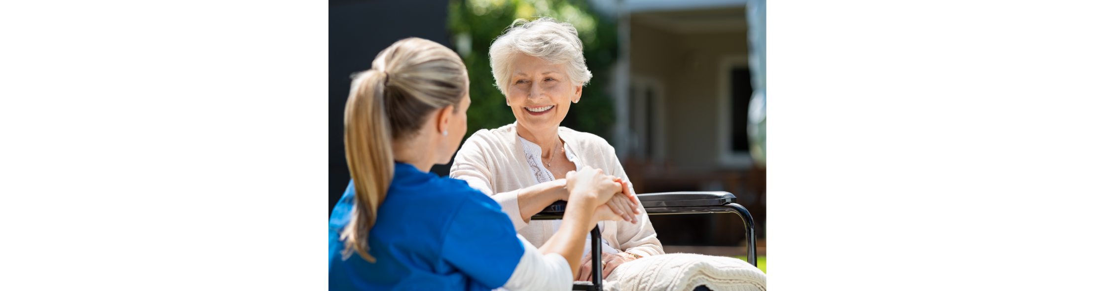 nurse kneeling down speaking to a woman in a wheelchair outside