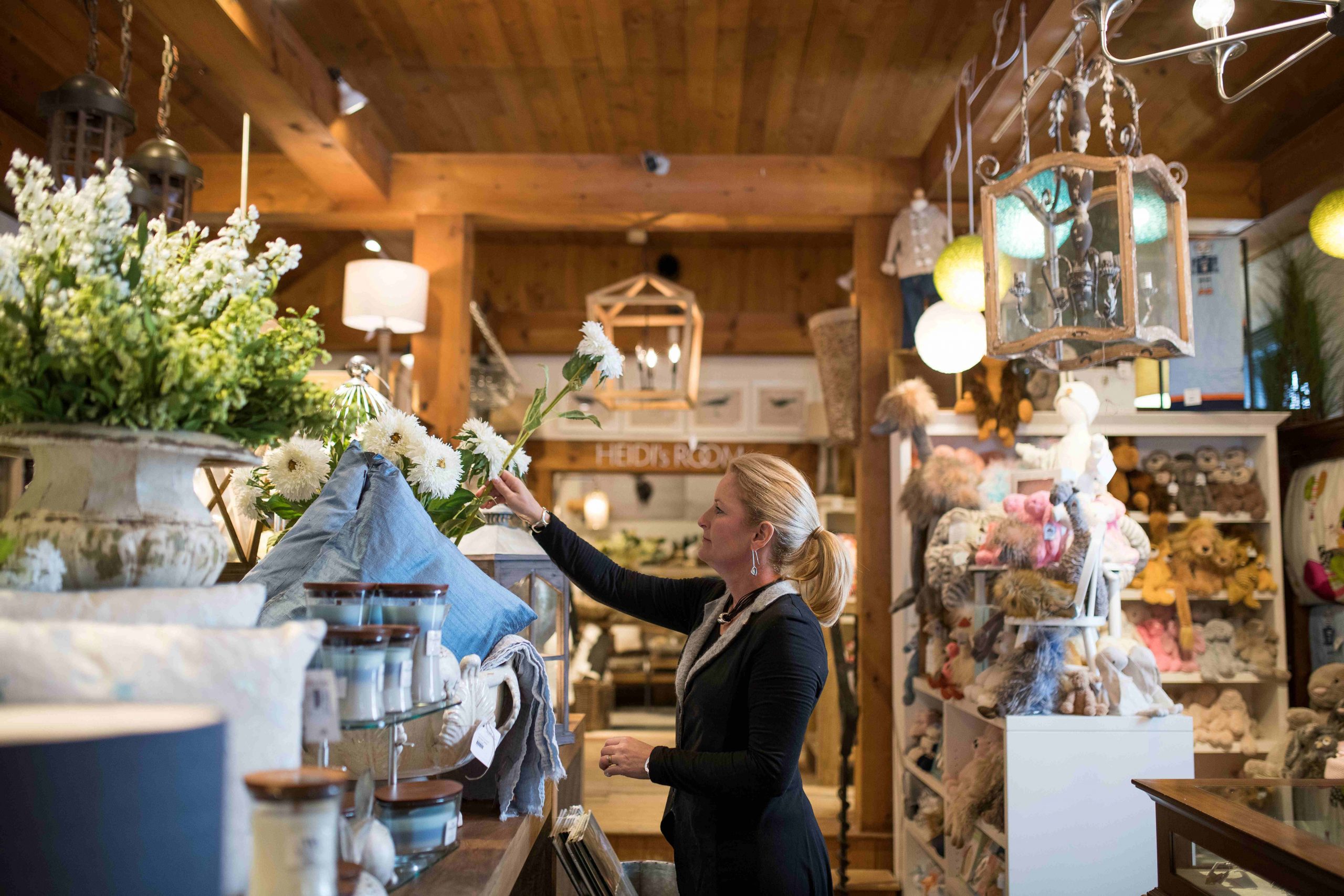 A shopkeeper places a flower in a vase.