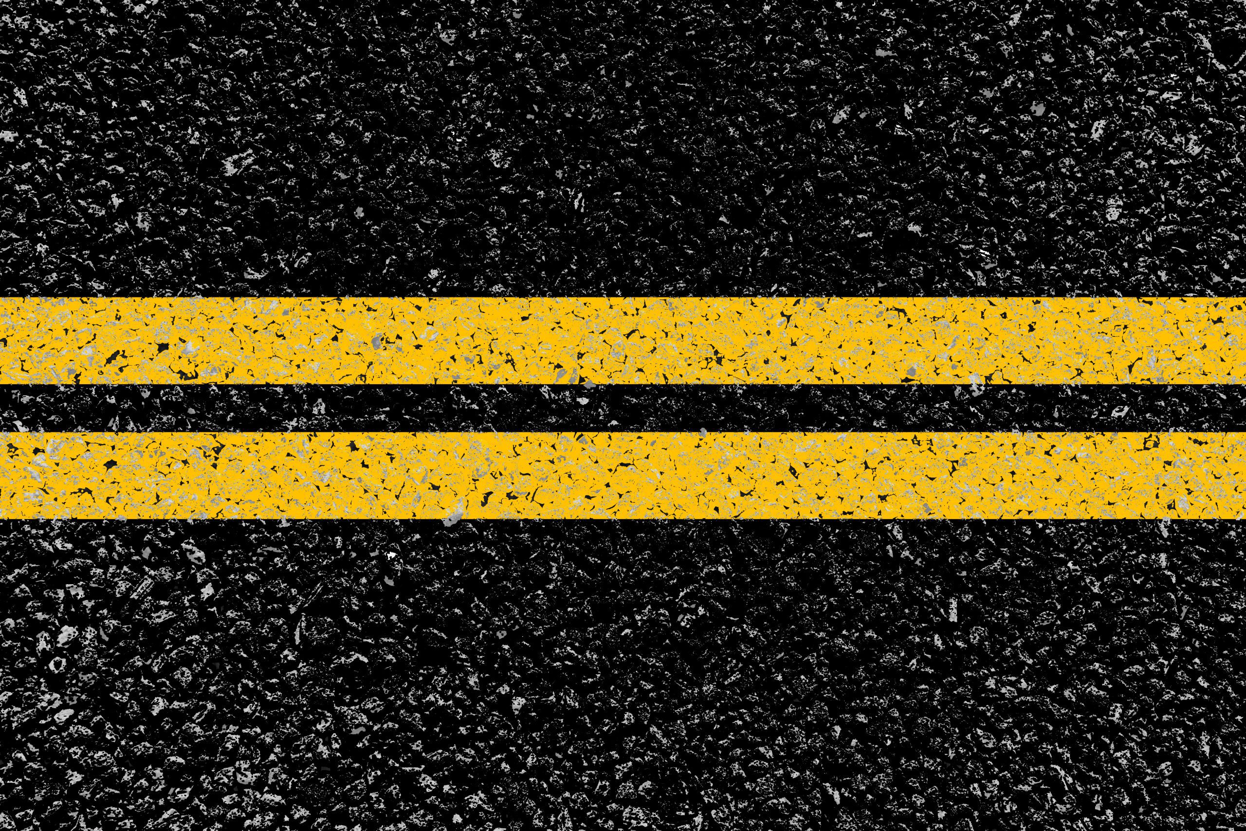 Two yellow lines are shown painted onto a black paved surface