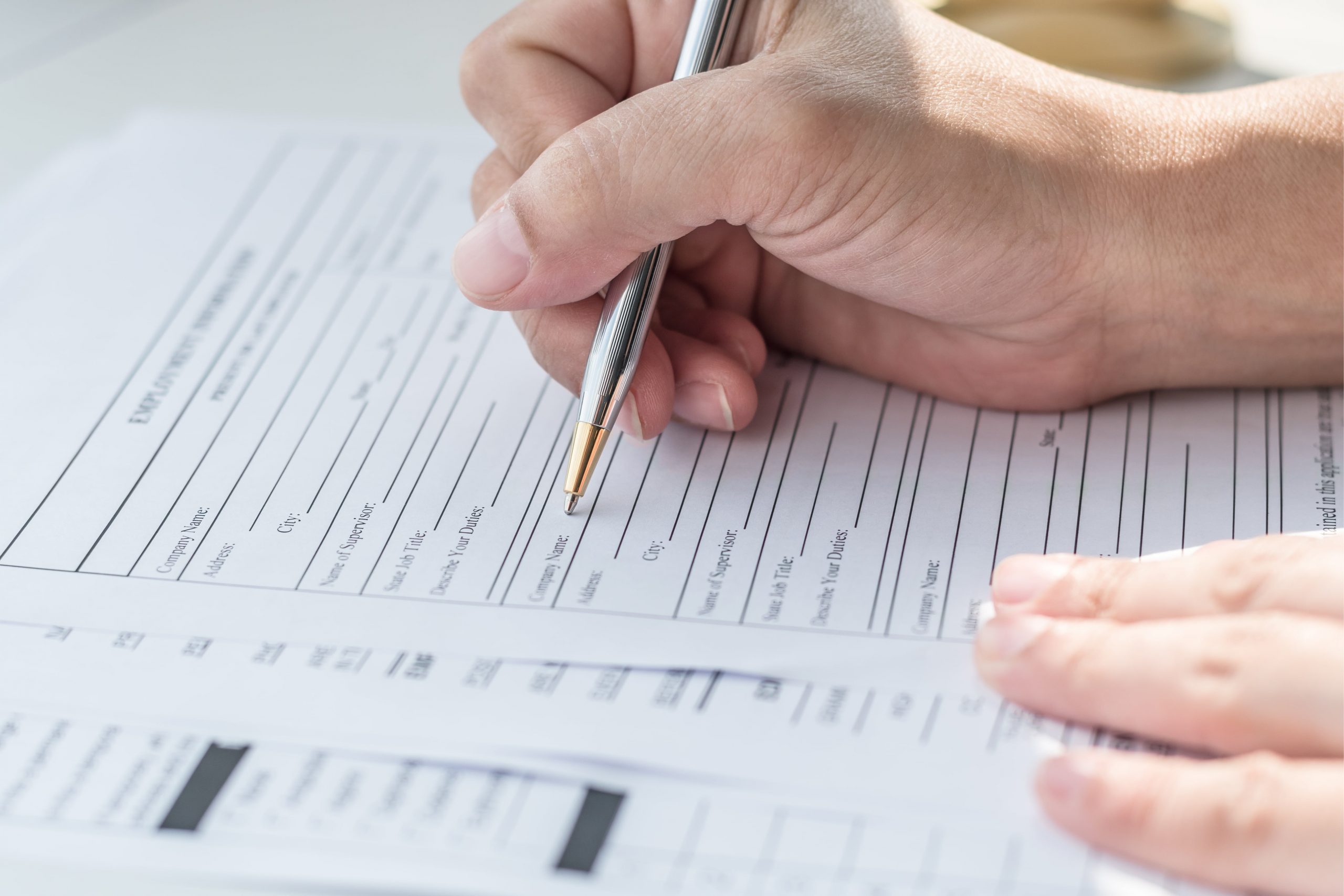 A hand holding a pen fills in application form